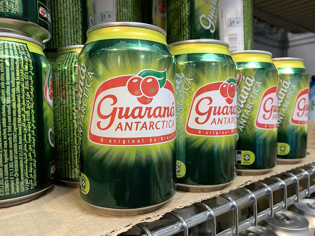 Alignement de canettes vertes de la boisson brésilienne Guaraná Antarctica sur une étagère de magasin.