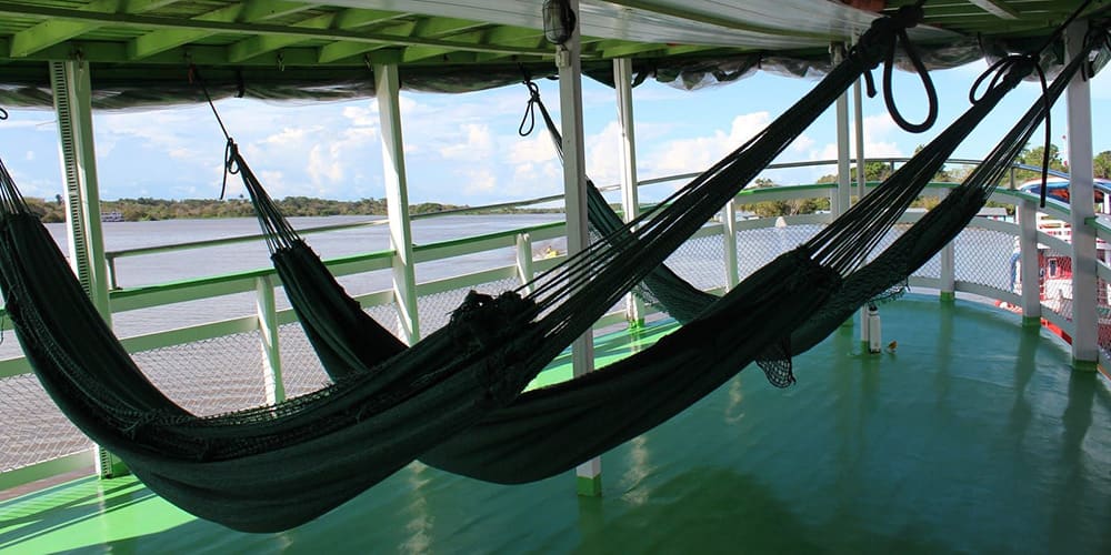 Hamacs suspendus sur le pont d’un bateau de croisière naviguant sur le fleuve Amazone