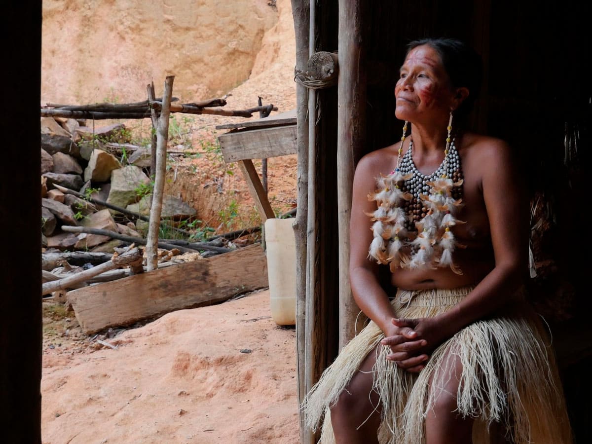  Une femme autochtone, ornée de peintures faciales et de colliers de plumes et de perles