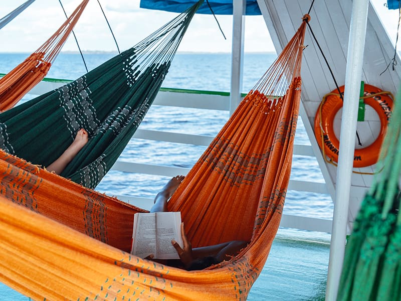 Personne lisant un livre dans un hamac sur un bateau en Amazonie