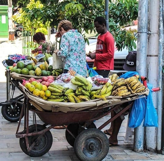 Marché de rue à Manaus avec des vendeurs de fruits tropicaux comme les bananes, mangues et papayes sur des charrettes.