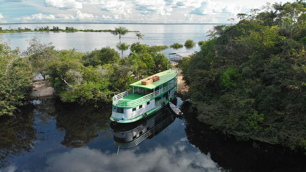 Bateau vert amarré dans un canal en pleine forêt amazonienne