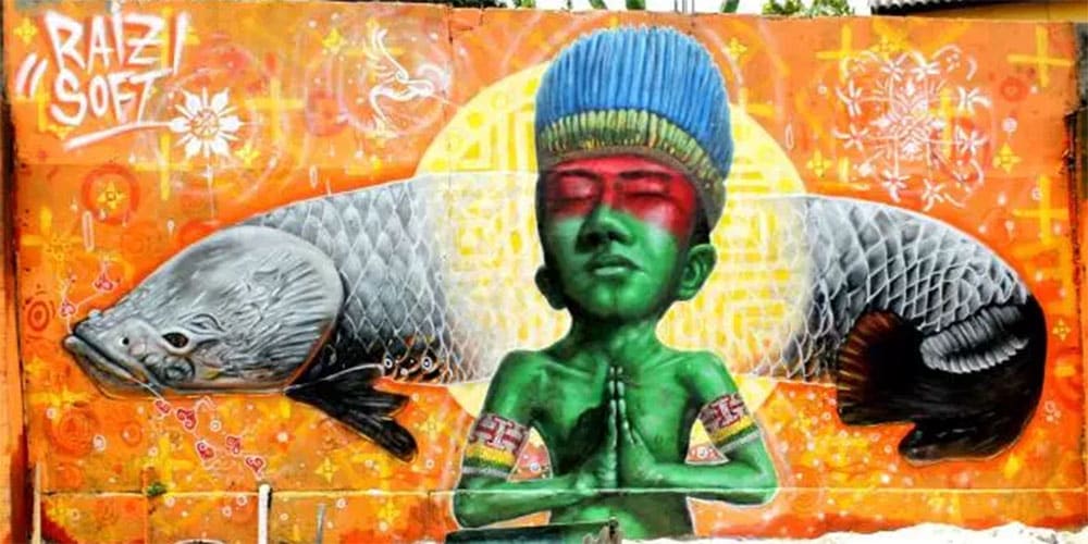 Fresque colorée représentant un enfant à la peau verte, les mains jointes dans une posture de prière, entouré de deux poissons arapaïmas symétriques.