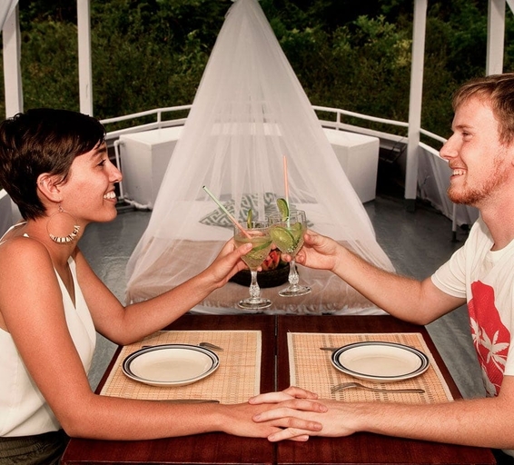 Un couple échange un toast avec des cocktails sur le pont d’un bateau en Amazonie