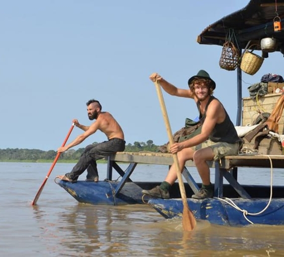 Deux hommes rament avec des pagaies en bois depuis leur radeau bleu