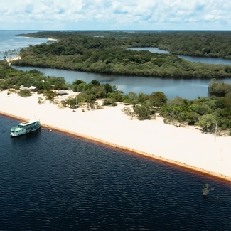 Vue aérienne d’un bateau amarré au bord d’une longue plage de sable blanc en Amazonie